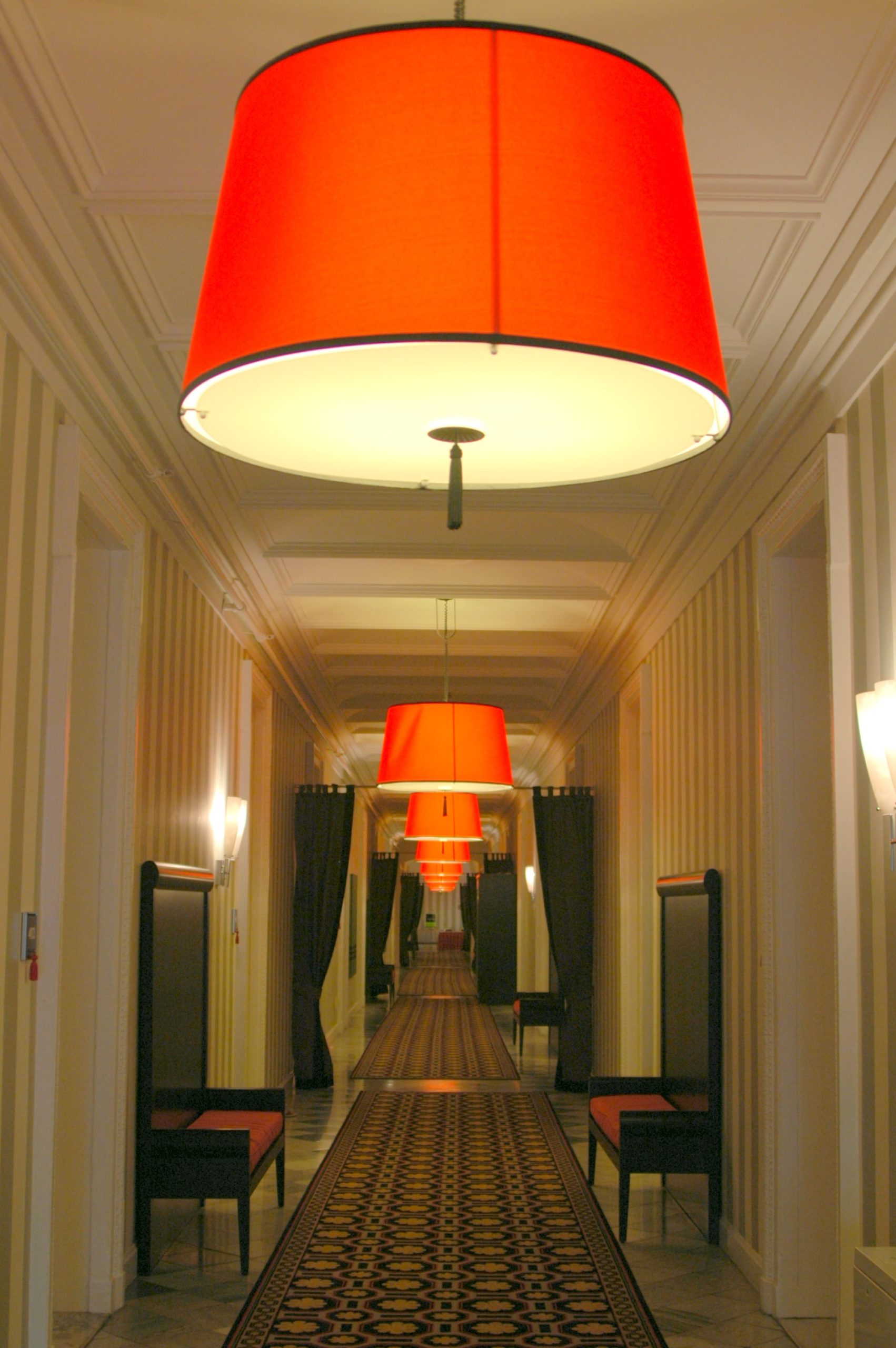 hotel hallway with circular red lamps hanging from the ceiling