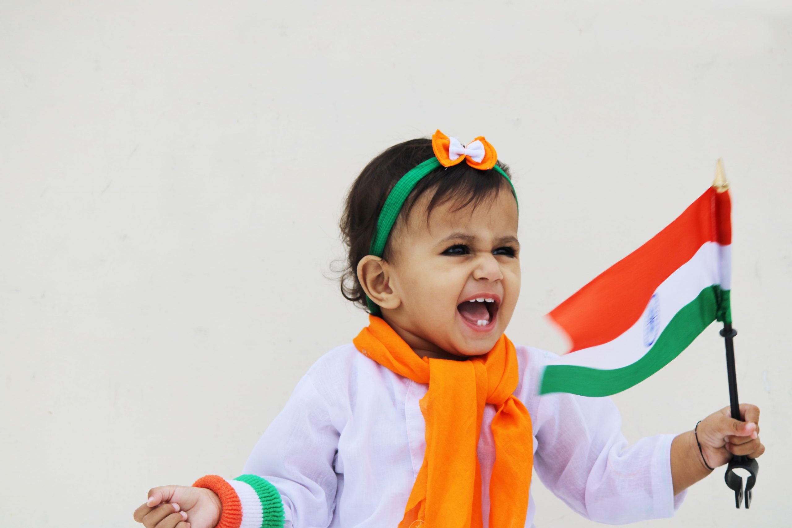 Child holding an Indian flag dressed in Indian flag colors