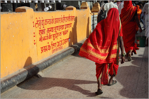 Women reading instruction written on a wall in Hindi.